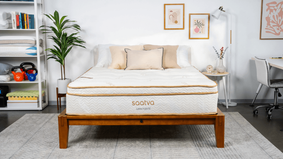Modern bedroom with a Saatva latex hybrid mattress on a wooden bed frame, surrounded by neutral decor and cozy accents.
